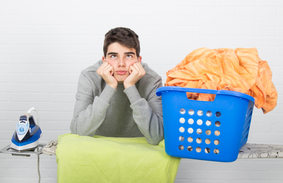 teenage boy looking unhappy about doing laundry